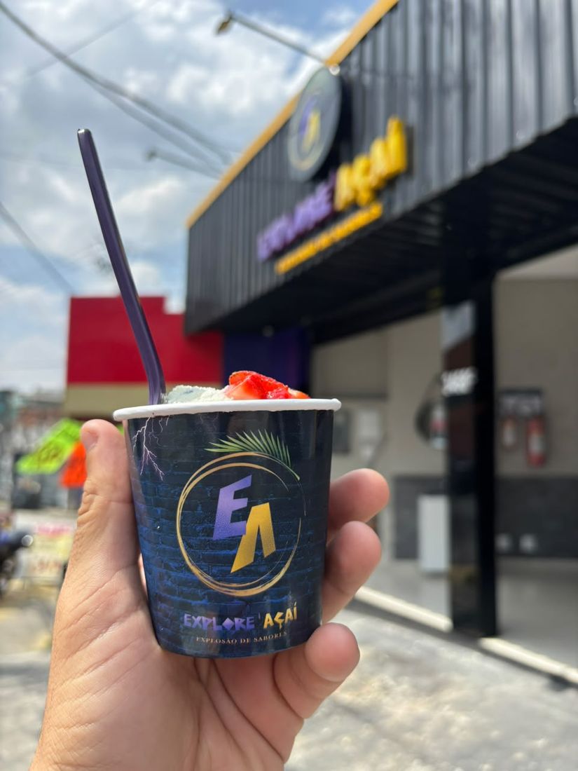 Copo Explore Açaí com morangos em frente a uma unidade da rede
